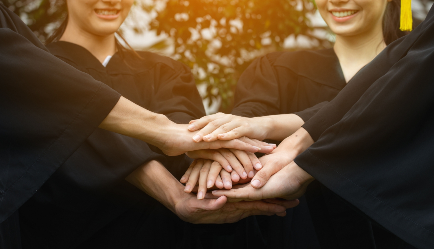 Rokas saliktas viena virs otras, fonā cilvēki