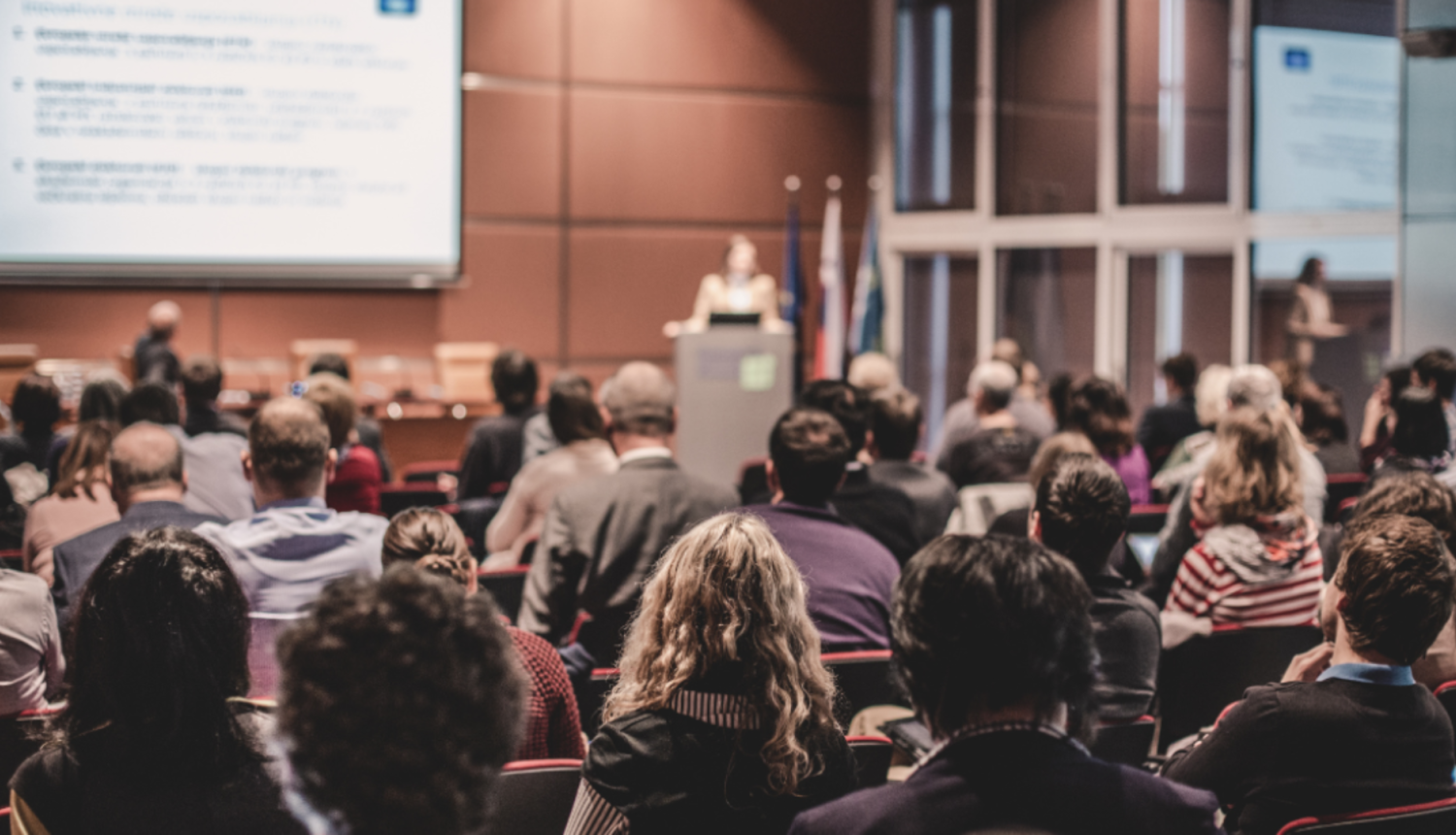 Cilvēku grupa sēž un klausās semināru