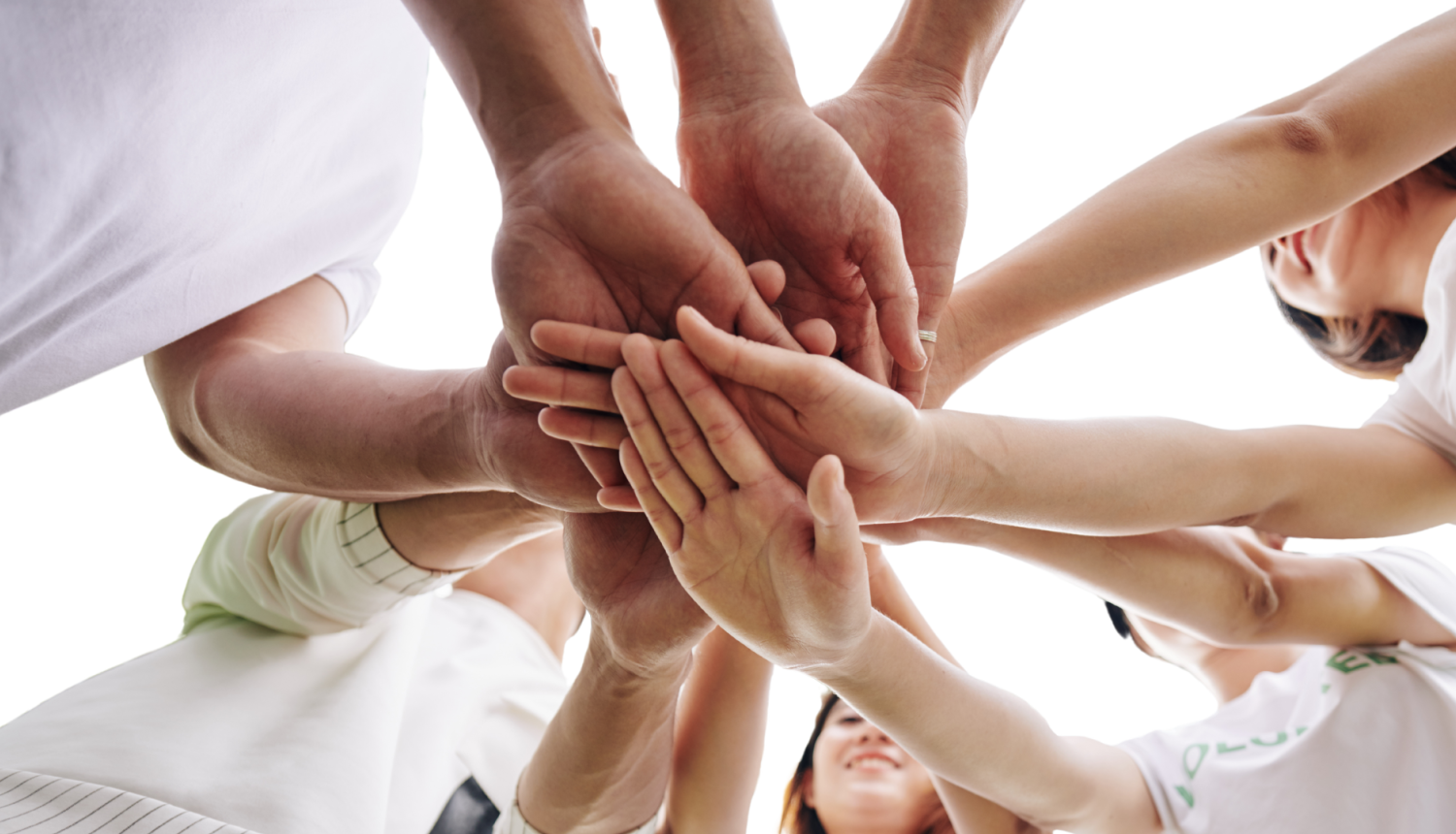 attēlā vairāki jauni cilvēki stāv aplī uz salika priekšā rokas kopā vienu otrai