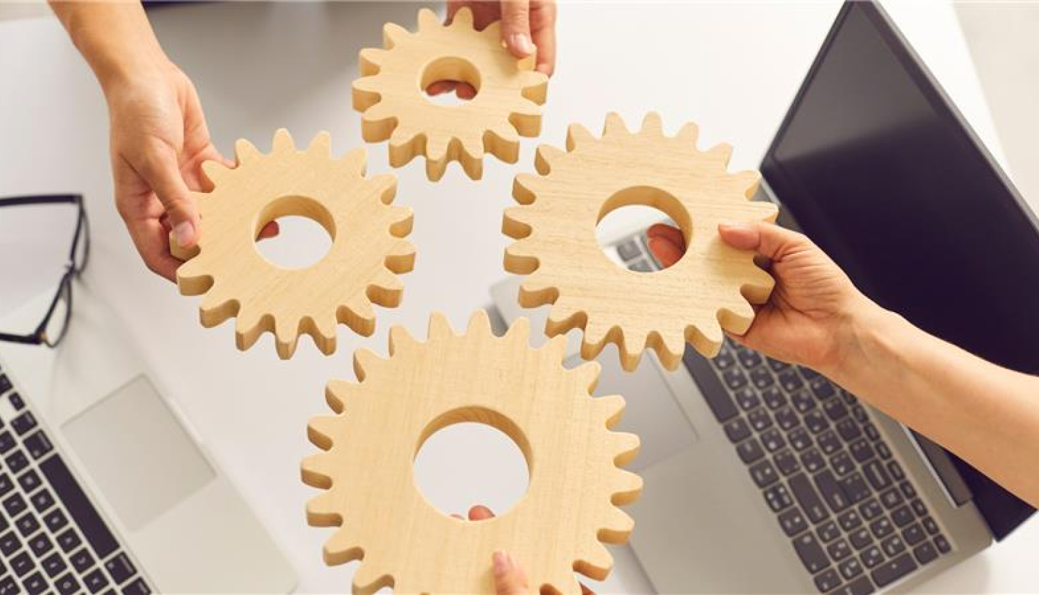 četri koka zobrati tiek salkti kopā no dažādām pusēm, tos tur rokās divi cilvēki virs datorgalda