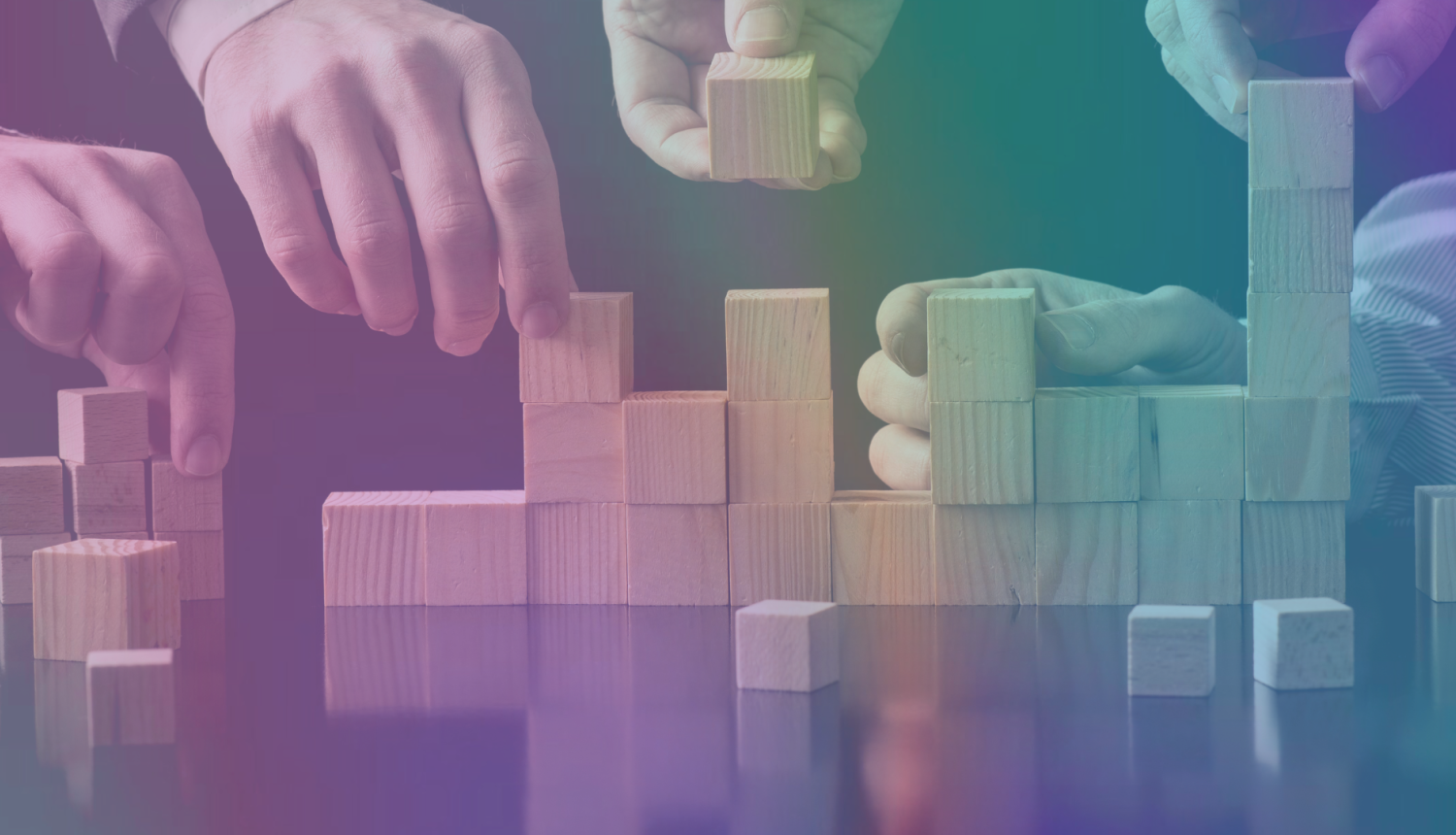 vairākas rokas liek uz galda koka klucīšus