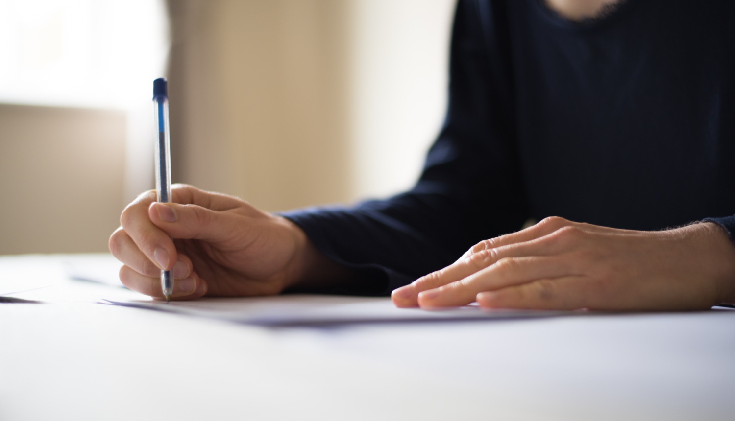 Cilvēks raksta ar pildspalvu