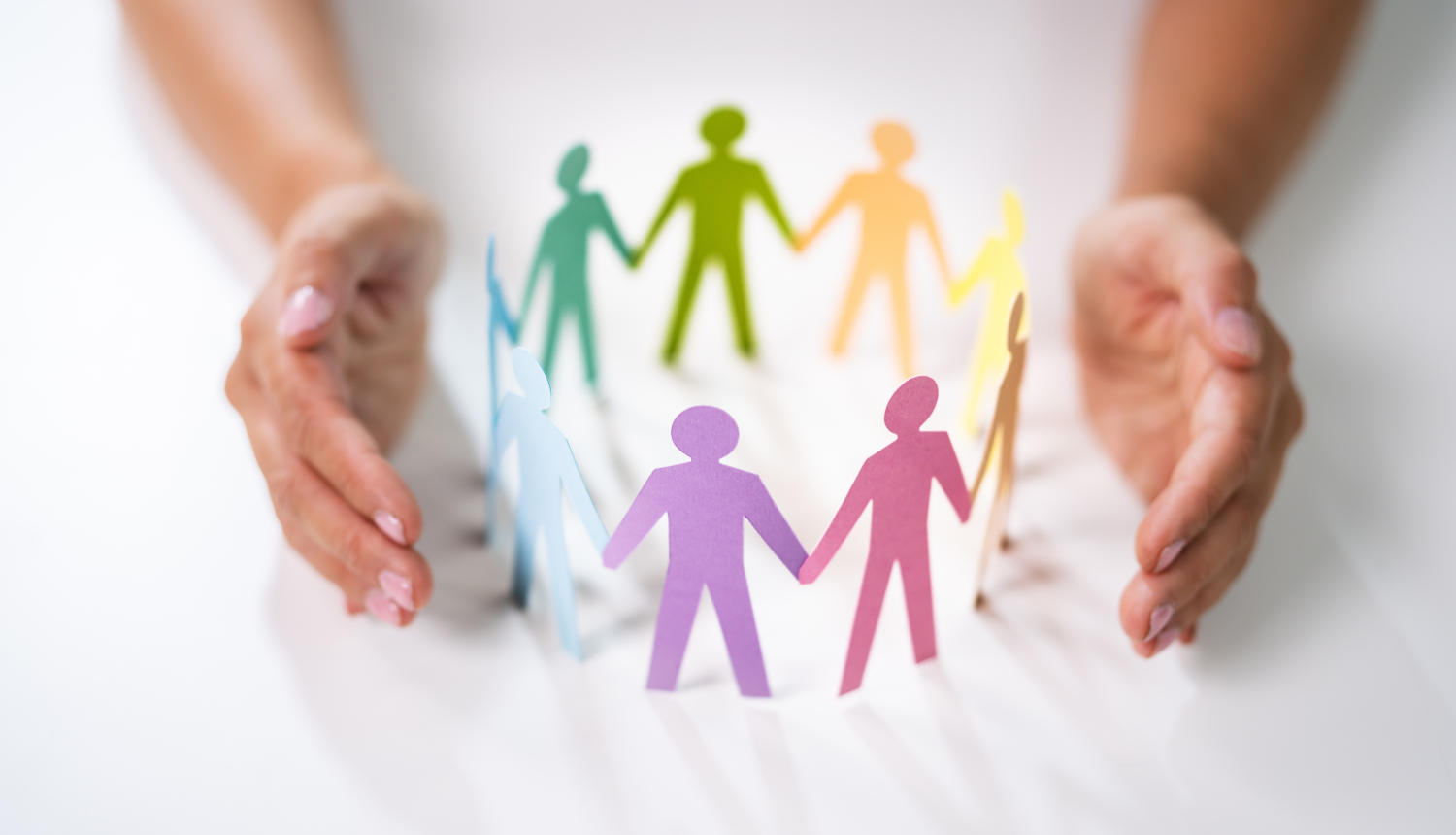 Cilvēks ar plaukstām apņem papīra cilvēka silueta figūriņas