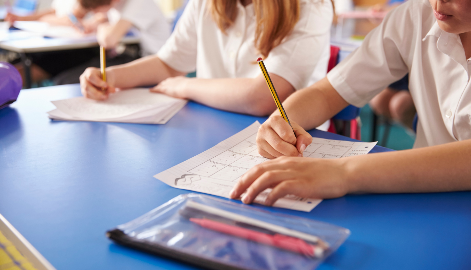 Skolēnu rokas ar zīmuļiem raksta uz papīra