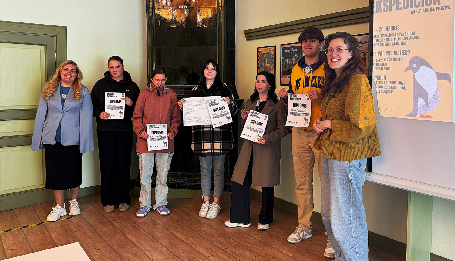 Jaunieši stāv grupā un pozē fotogrāfam