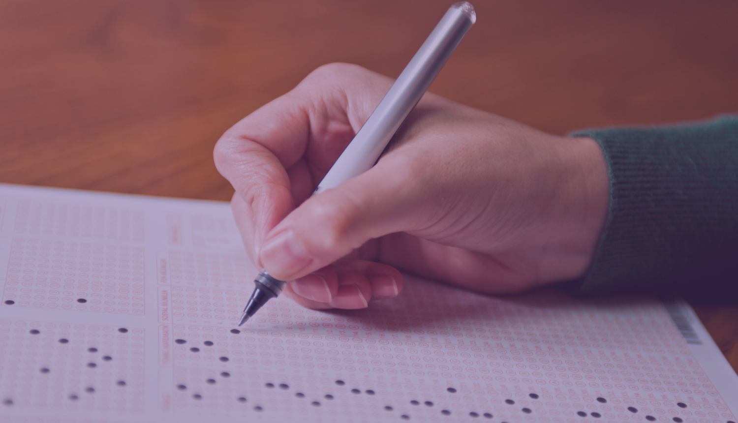 rokā tur pildspalvu un pilda testu uz lapas