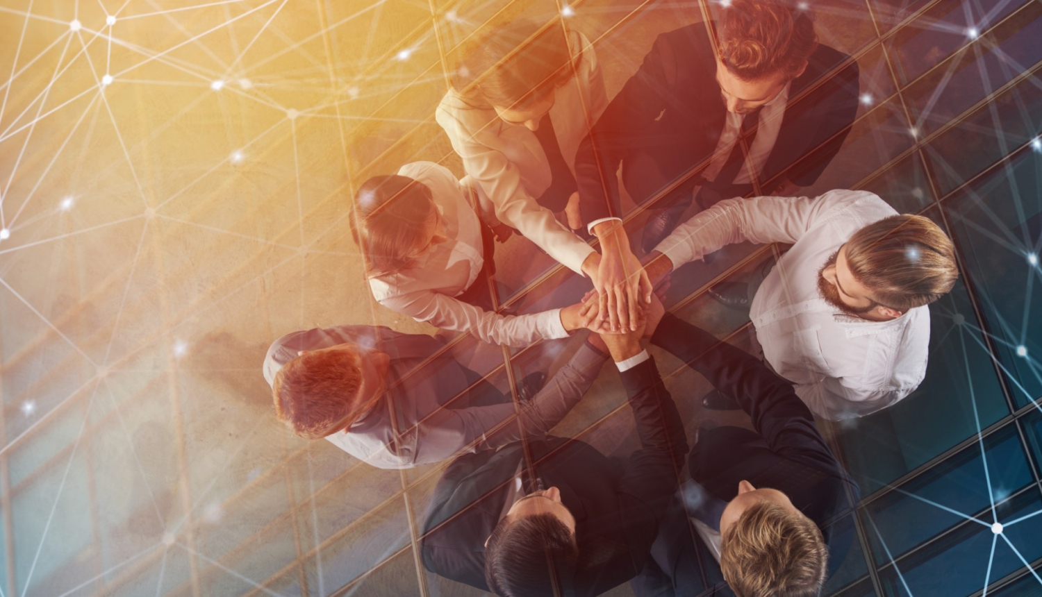 vairāki cilvēki stāv aplī un salika savas rokas vienu virs otru 