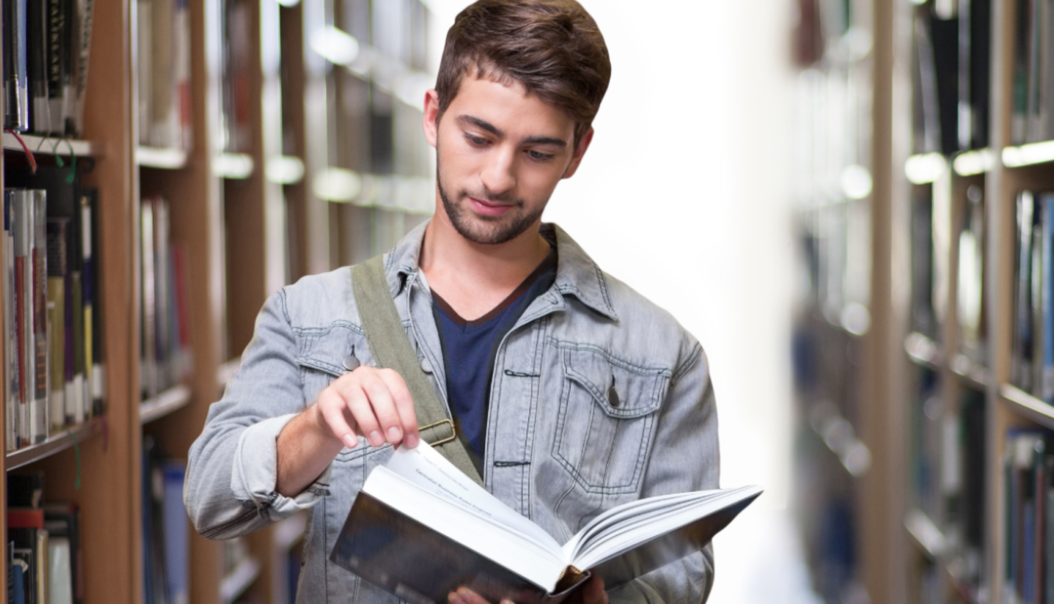 Vīrietis lasa grāmatu bibliotēkā