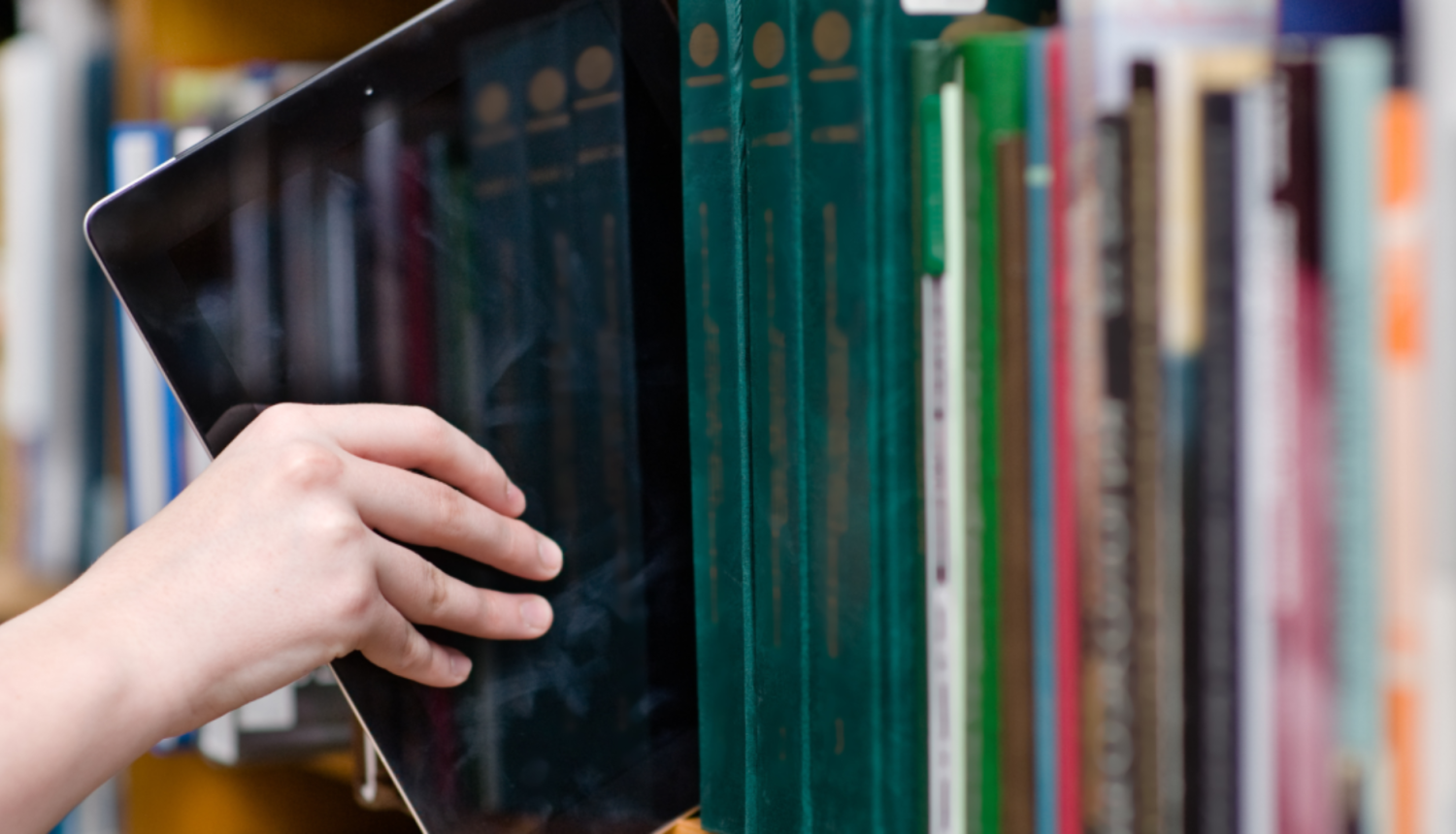 Digitālo planšeti ievieto plauktā starp grāmatām