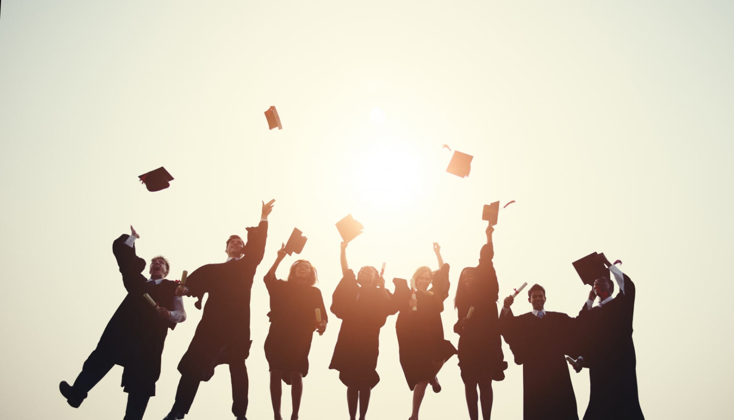 Erasmus studenti priecīgi lec un met gaisā absolventu cepures