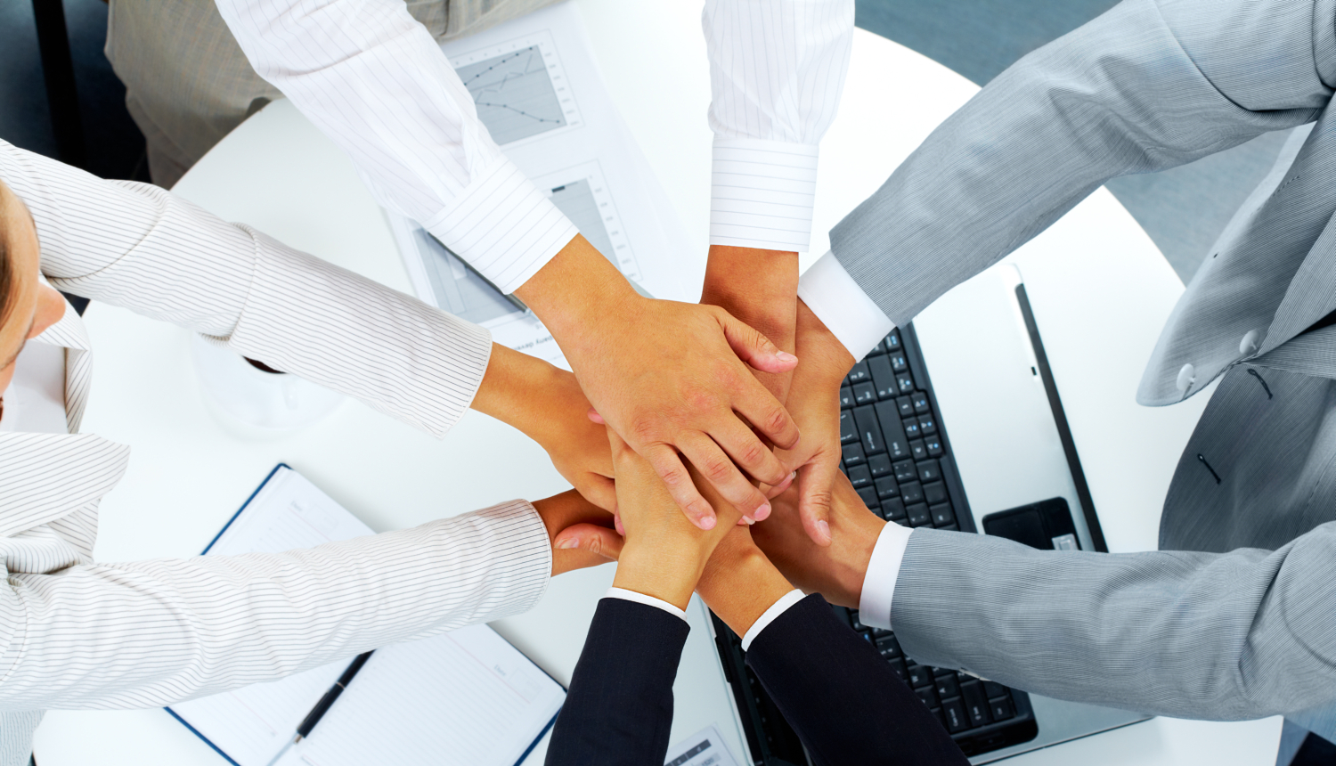 Seminārā virs galda dalībnieki ir salikuši rokas rokā, lai simbolizētu komandu