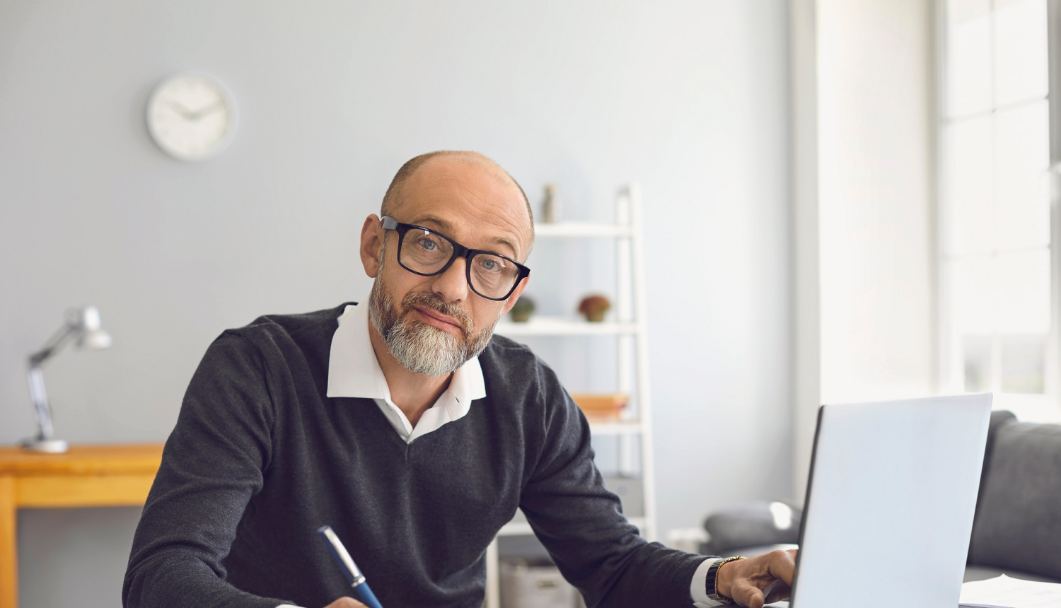 Vīrietis strādā pie datora un pieraksta informāciju