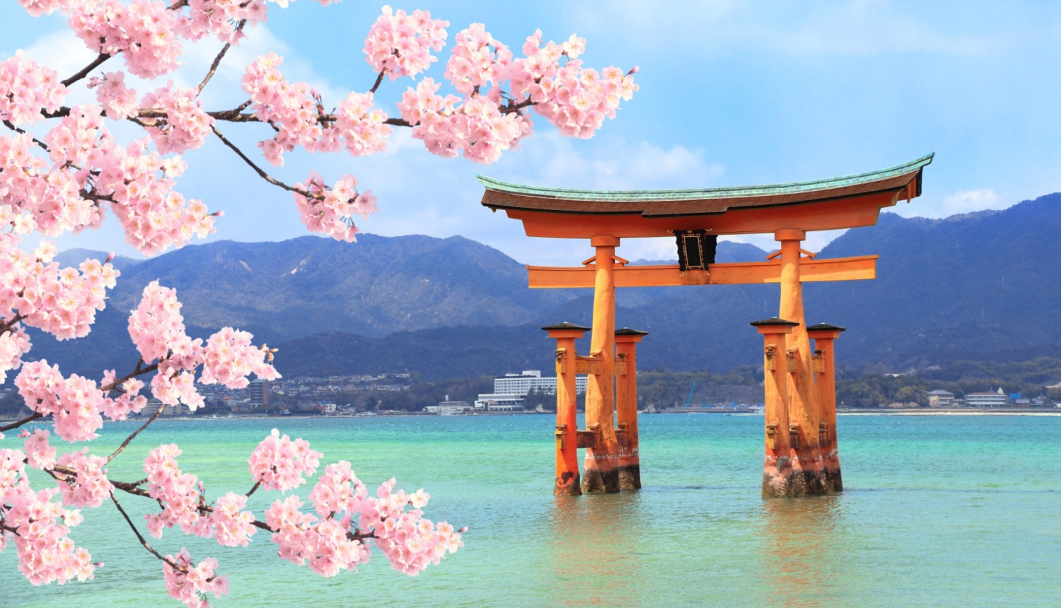 skats uz Japānas kalniem ar ezeru priekšplānā ziedošās sakuras zariņi