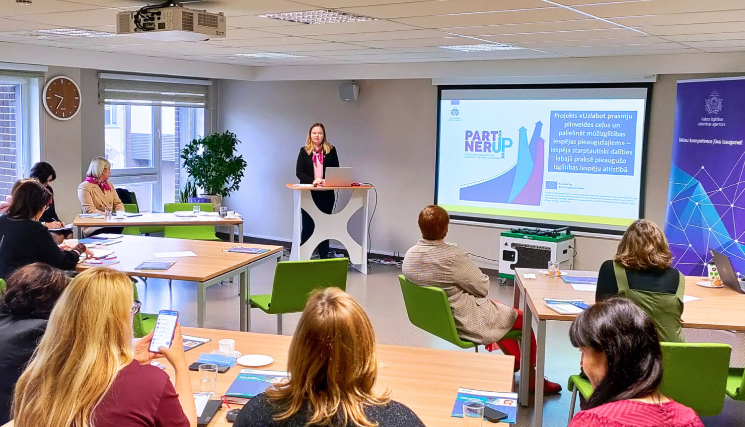 Cilvēki sēž un klausās semināru