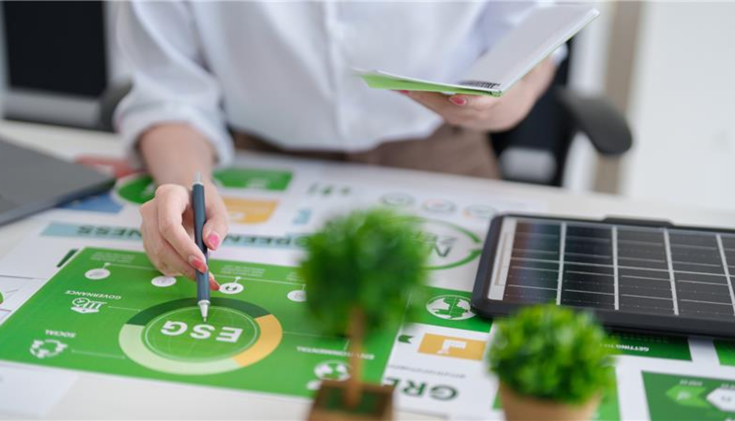 Erasmus seminārs par vidi, klimatu un zaļo pāreju, sieviete pie galda atzīmē ar pildspalvu zaļā zīmējumā