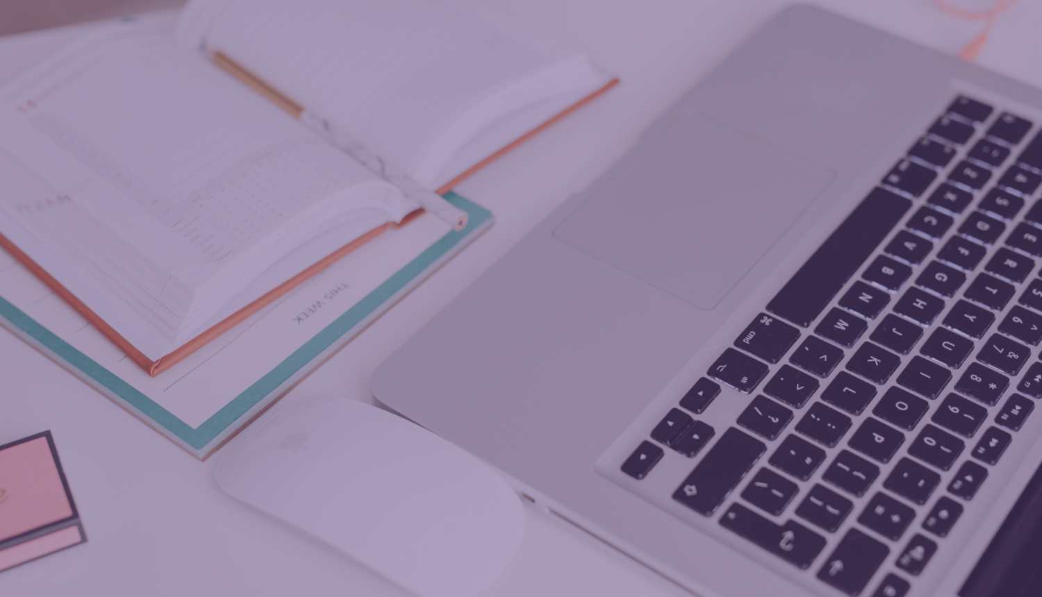 portatīvais dators atvērts uz galda un blakus atvērta pierakstu klade