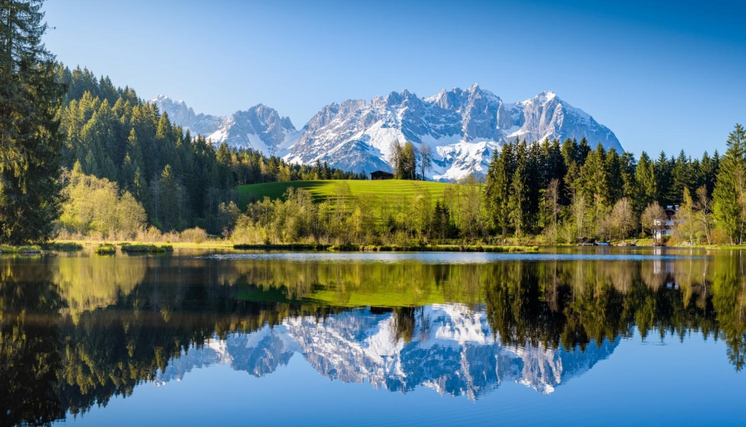 Austrijas dabas skats ar apsnigušiem kalniem uz ezeru priekšplānā