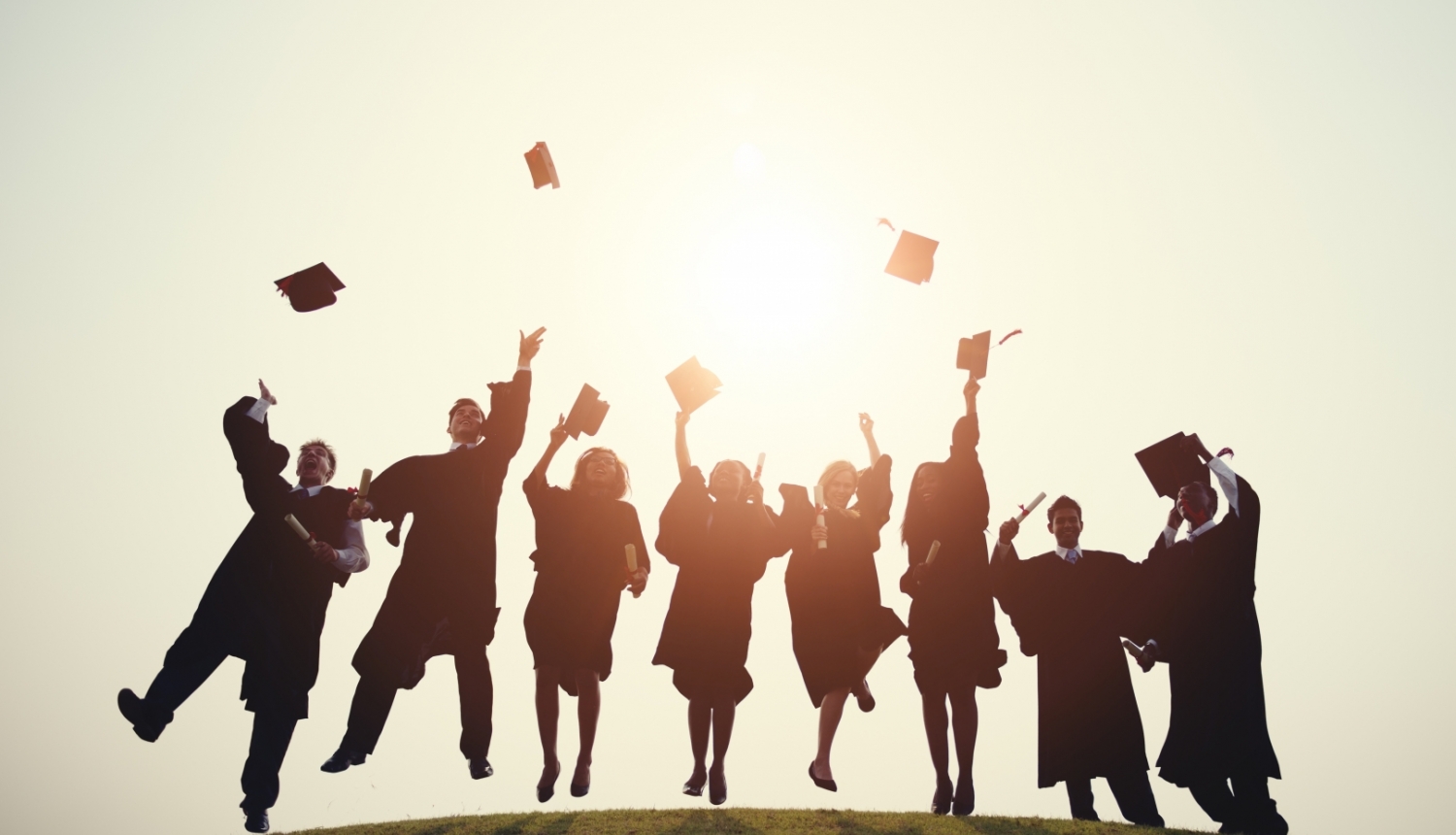 Erasmus studenti priecīgi lec un met gaisā absolventu cepures