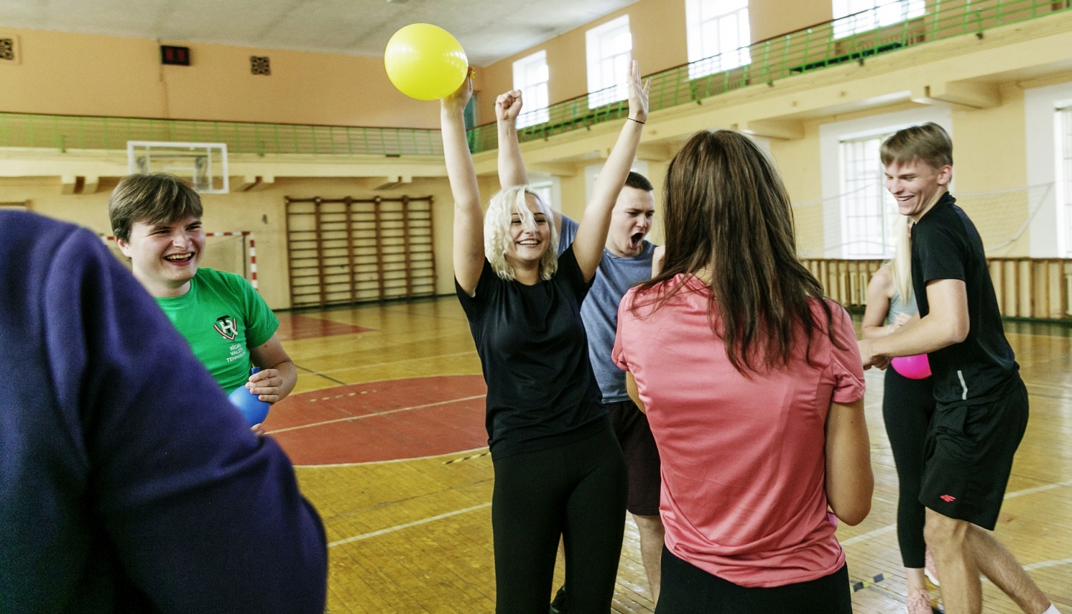 Priecīga meitene sporta zālē ar balonu rokās