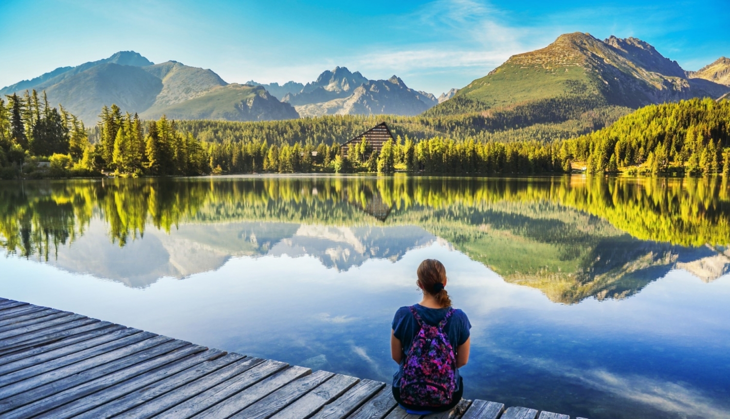 dabas skats uz Slovākias kalniem priekšā  uz laipas sēž ar muguru jauna meitene uz skatās uz dabu