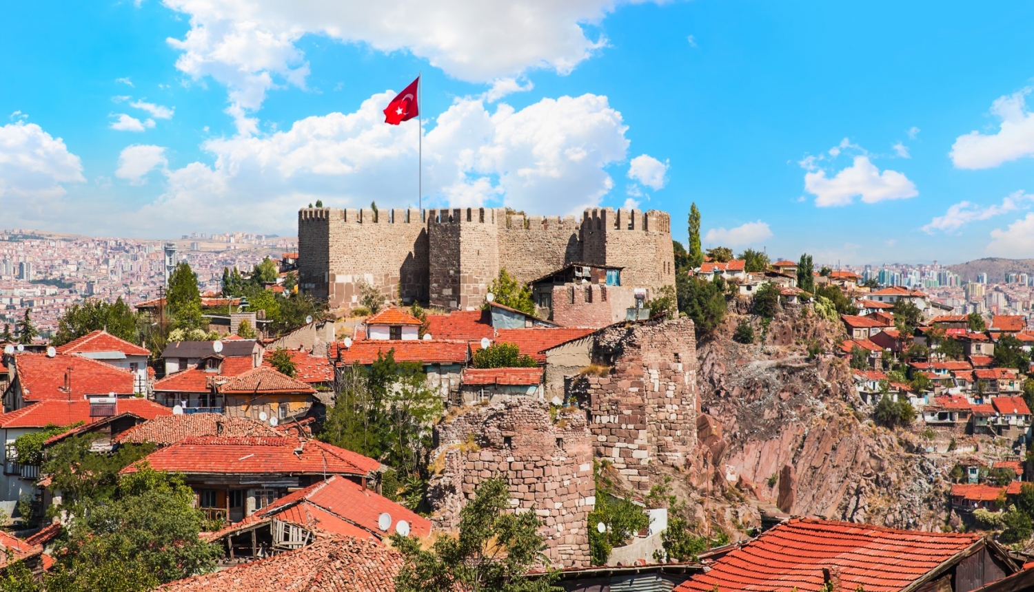 skats uz Turcijas pilsētu ar pili un Turcijas karogu