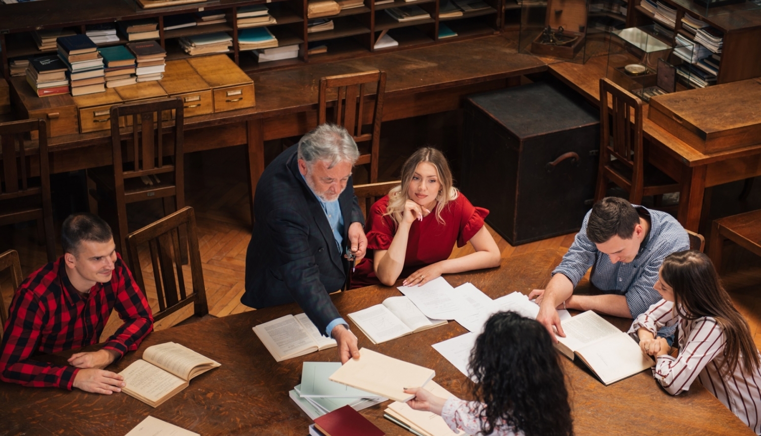 Pasniedzējs bibliotēkā ar studentiem mācās